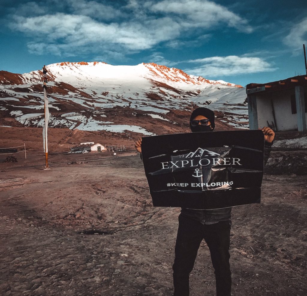A Travel Photographer bearing a flag in Spiti